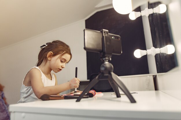 Pequeño blogger lindo con cosméticos grabando video en casa