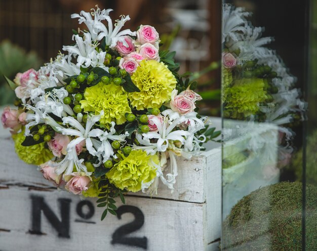 Un pequeño y bonito ramo de flores de colores dentro de una caja de madera blanca.