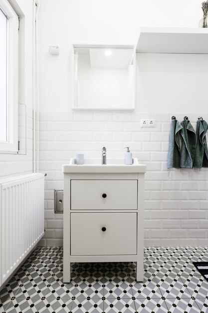 Pequeño cajón blanco en un baño blanco con artículos de higiene.