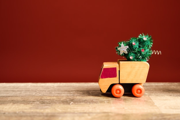 Pequeño camión de juguete que lleva un árbol de navidad