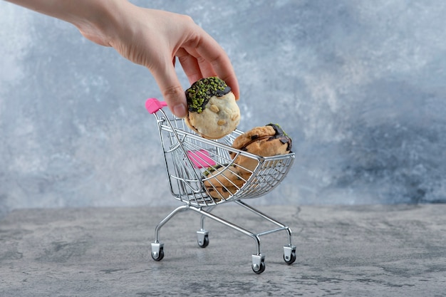 Un pequeño carrito rosa de sabrosas galletas con chispitas sobre una mesa de mármol.