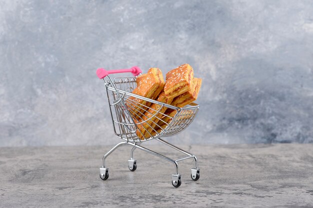 Un pequeño carrito rosa de sabrosas galletas sobre una mesa de mármol.