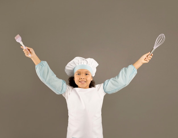 Foto gratuita pequeño chef feliz con utensilios de cocina