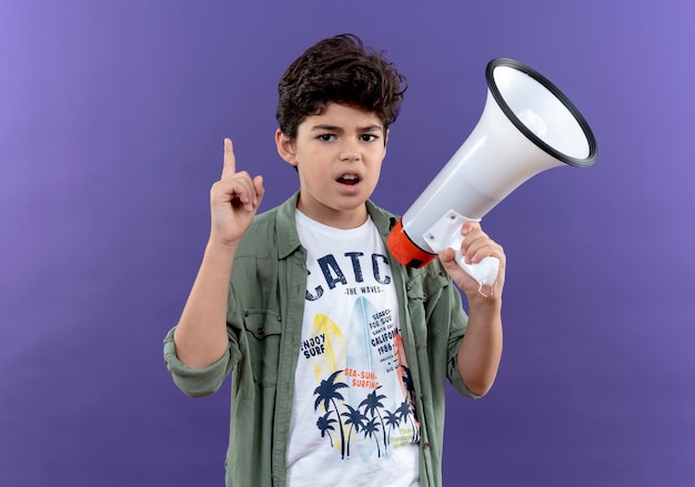 Foto gratuita pequeño colegial impresionado sosteniendo el altavoz y apunta hacia arriba aislado en la pared púrpura