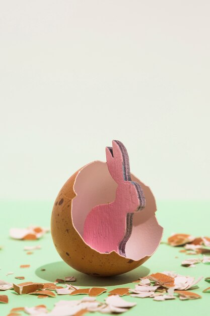 Pequeño conejo rosa de madera en huevo roto.