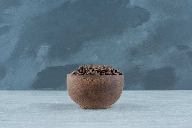 Un pequeño cuenco de madera con granos de café sobre fondo blanco. foto de alta calidad