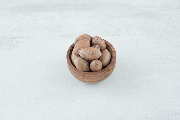 Un pequeño cuenco de madera de nueces sobre fondo blanco. Foto de alta calidad