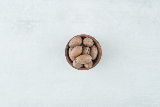 Un pequeño cuenco de madera de nueces sobre fondo blanco. Foto de alta calidad