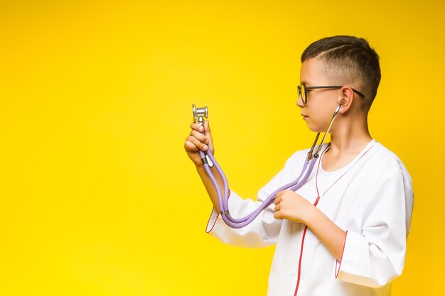 Un pequeño doctor sonriente con estetoscopio, aislado en amarillo.