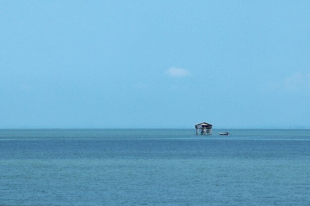 Pequeño edificio en el mar bajo la luz del sol y un cielo azul durante el día