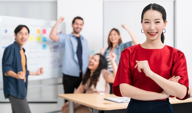 Pequeño emprendedor asiático inteligente de pie retrato confiado con amigos socios reunión informal lluvia de ideas con pizarra blanca y análisis de gráficos de papel de finanzas comerciales en el fondo de la oficina