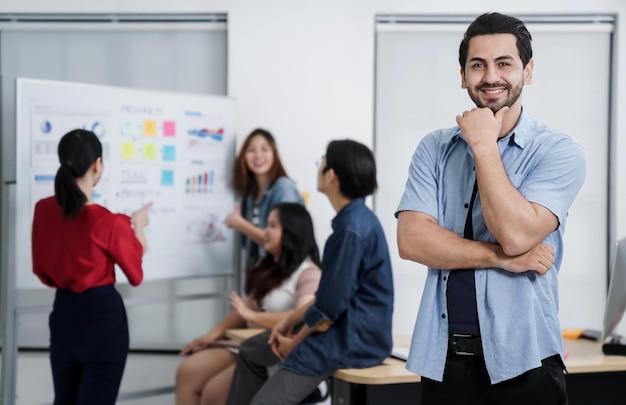 Pequeño emprendedor asiático inteligente de pie retrato confiado con amigos socios reunión informal lluvia de ideas con pizarra blanca y análisis de gráficos de papel de finanzas comerciales en el fondo de la oficina