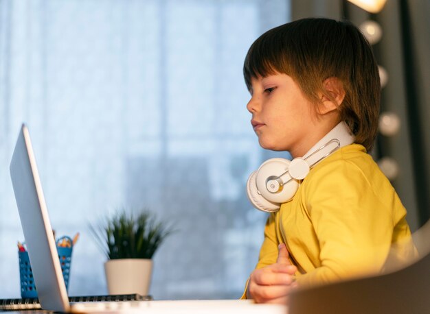 Pequeño estudiante en línea con auriculares