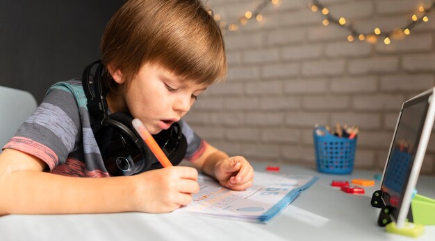 Foto gratuita pequeño estudiante en línea escribiendo y concentrado