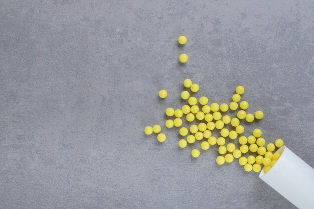 Un pequeño frasco blanco de pastillas de ácido ascórbico sobre superficie gris