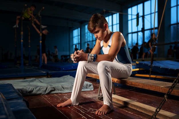 Pequeño gimnasta masculino entrenando en gimnasio, flexible y activo