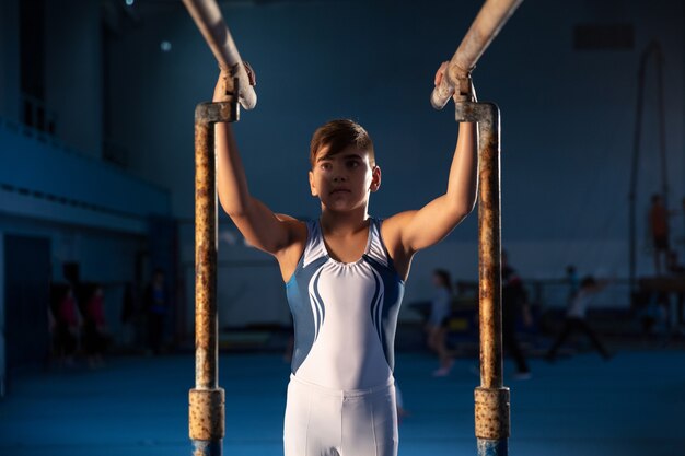 Pequeño gimnasta masculino entrenando en gimnasio flexible y activo