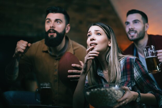 Pequeño grupo de amigos anticipando el final de un partido de rugby mientras ve el juego en la televisión