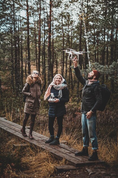 Un pequeño grupo de personas está disfrutando de su caminata en el parque forestal de otoño, uno de ellos está haciendo una foto a través de un dron.