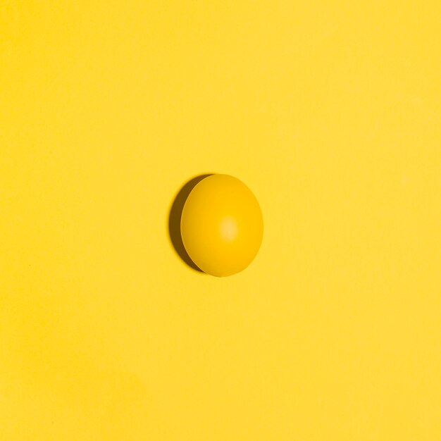 Pequeño huevo de Pascua amarillo en mesa amarilla