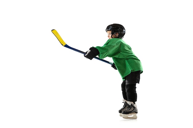 Pequeño jugador de hockey con el palo en la cancha de hielo, pared blanca del estudio