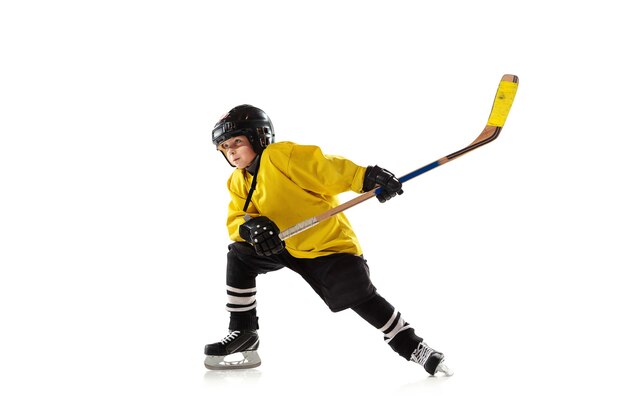 Pequeño jugador de hockey con el palo en la cancha de hielo y pared blanca