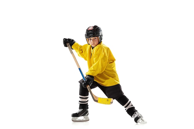 Pequeño jugador de hockey con el palo en la cancha de hielo y pared blanca