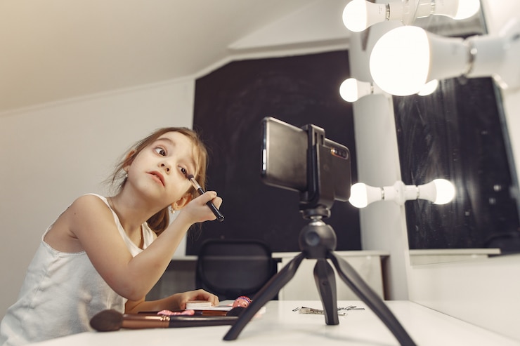 Foto gratuito el pequeño y lindo blogger con cosméticos grabando un video en casa.