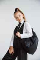 Foto gratuita pequeño modelo caucásico femenino posando en uniforme escolar con mochila sobre fondo blanco.