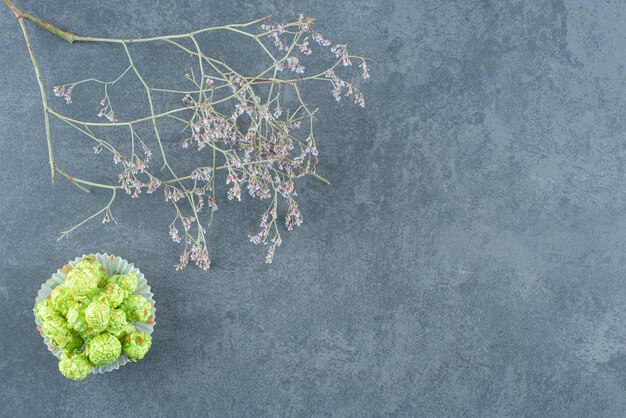 Pequeño montón de dulces de palomitas de maíz verde junto a ramas decorativas en mármol