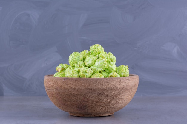 Pequeño montón de dulces de palomitas de maíz verde en un recipiente de madera sobre fondo de mármol. Foto de alta calidad