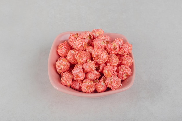 Un pequeño montón de palomitas de maíz con sabor en una bandeja de color rosa sobre la mesa de mármol.