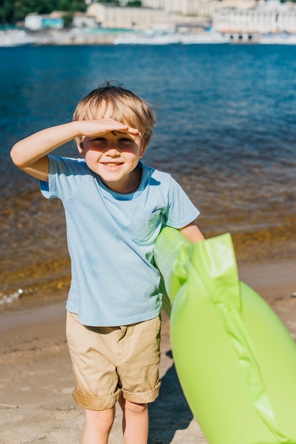 Foto gratuita pequeño muchacho lindo que sonríe en la playa