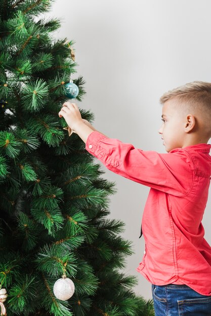 Pequeño niño decorando árbol de navidad