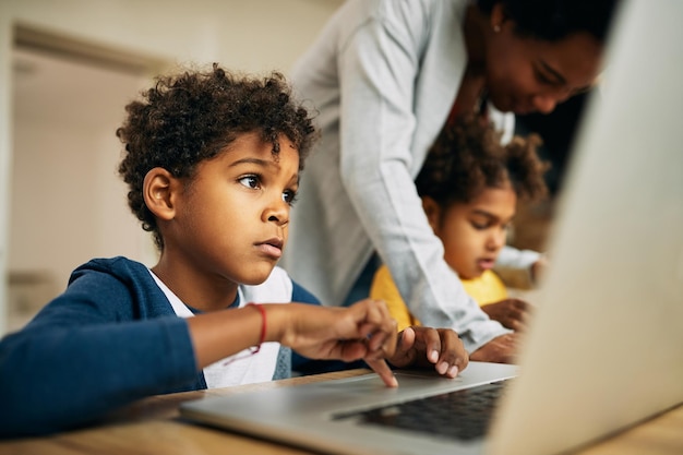 Pequeño niño negro elearning en una computadora en casa