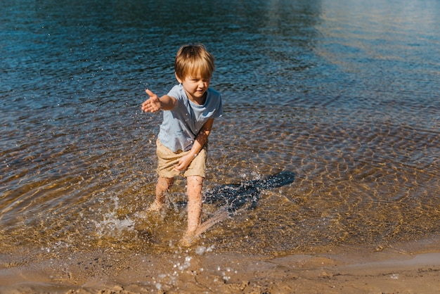 Pequeño niño salpicando agua en la playa