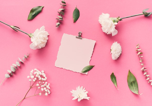 Pequeño papel en blanco con flores en la mesa