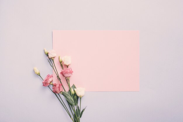 Pequeño papel con flores color de rosa en mesa de luz