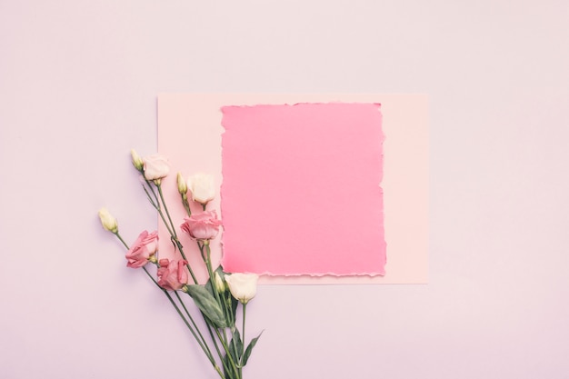 Foto gratuita pequeño papel con flores color de rosa en la mesa