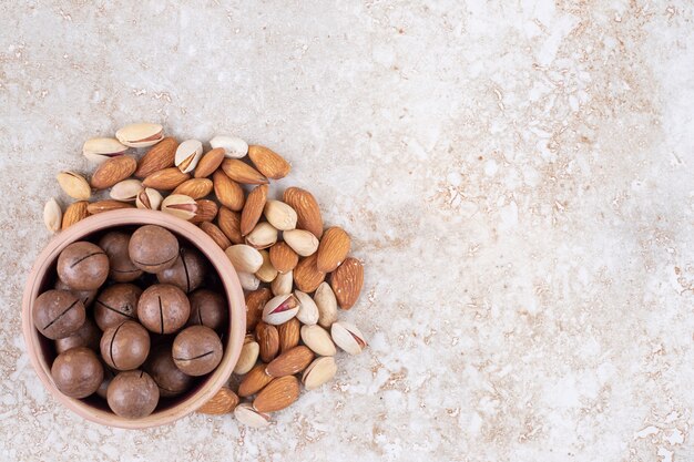 Un pequeño paquete de almendras y pistachos alrededor de un cuenco de bolas de chocolate.