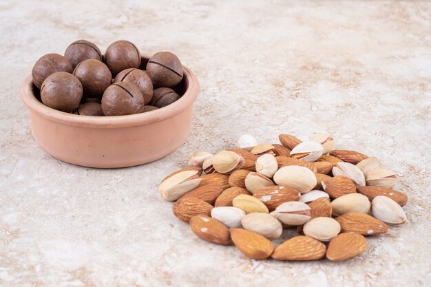 Un pequeño paquete de almendras y pistachos junto a un cuenco de bolas de chocolate.