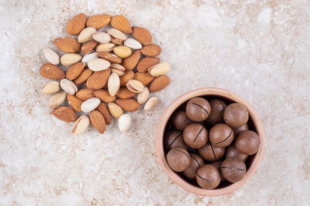 Un pequeño paquete de almendras y pistachos junto a un cuenco de bolas de chocolate.