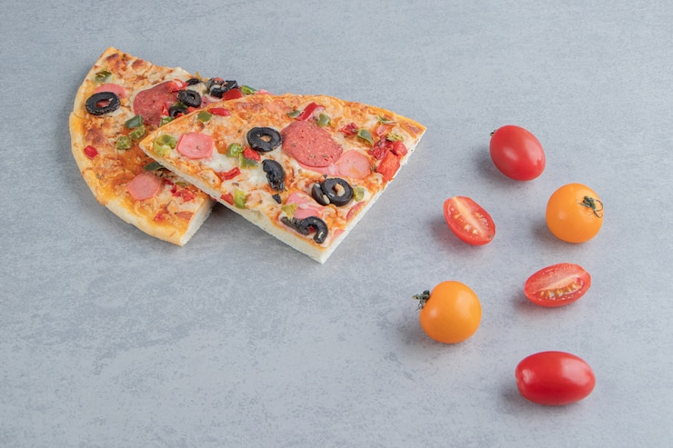 Foto gratuito pequeño paquete de tomates y rebanadas de pizza en mármol