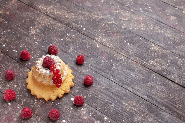 Pequeño pastel simple con azúcar en polvo, frambuesa y arándanos en un escritorio rústico marrón, pastel de frutos rojos horneado dulce