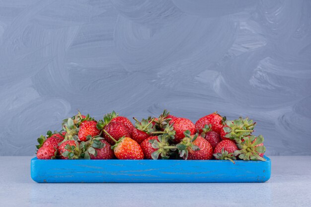 Foto gratuita pequeño plato azul con una porción de fresas sobre fondo de mármol.