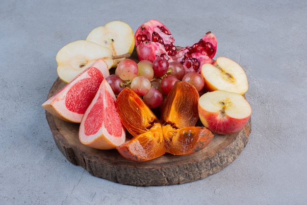 Un pequeño surtido de frutas sobre una tabla de madera sobre fondo de mármol.