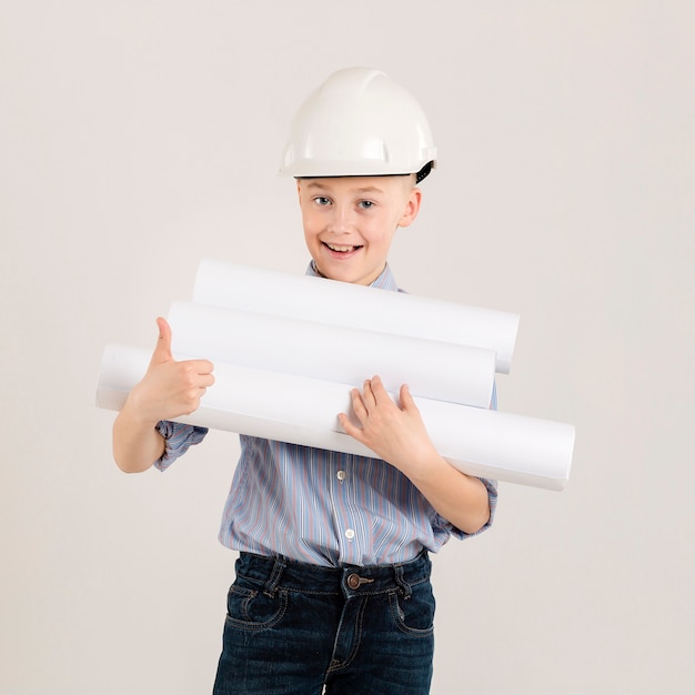 Foto gratuita pequeño trabajador de la construcción que muestra los pulgares para arriba