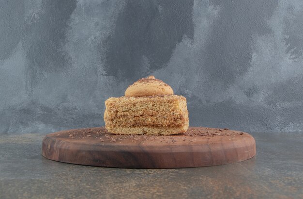 Pequeño trozo de pastel cubierto con una galleta en una tabla