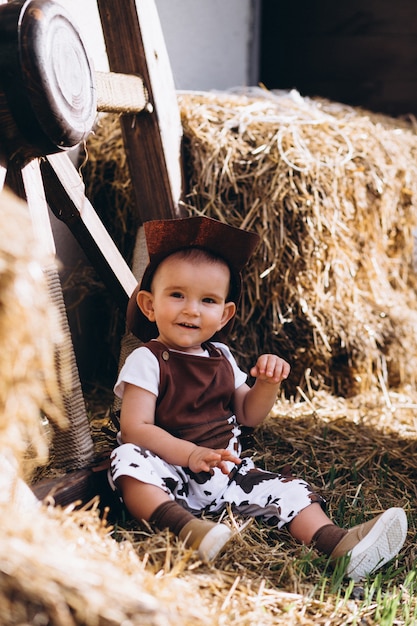 Foto gratuita pequeño vaquero sentado en el heno