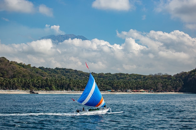 Pequeño velero flota en el agua con impresionantes vistas a la montaña.